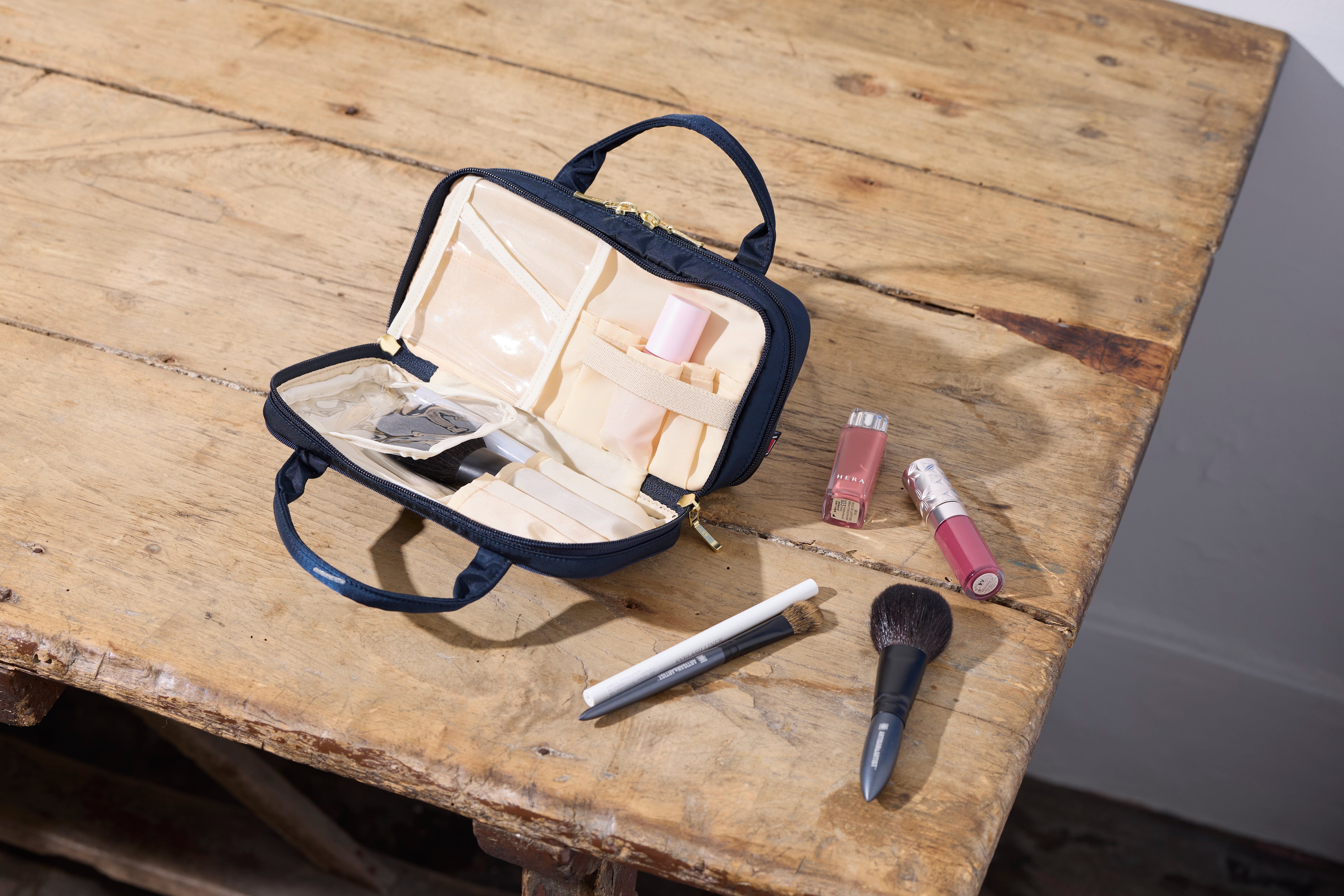 Artisan & Artist 5OP-ER22 Cosmetic Pouch in Navy with Top Handles and Multi-Compartment Interior.
